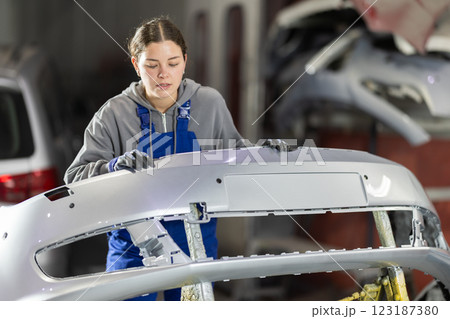 Service station young woman employee works in repair box, department 123187380