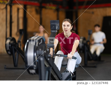 Woman exercising on a rowing machine Woman exercising on a rowing machine 123187446