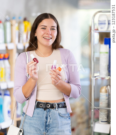 Female buyer chooses nail polish in household goods department of supermarket Female buyer chooses nail polish in household goods department of supermarket 123187531