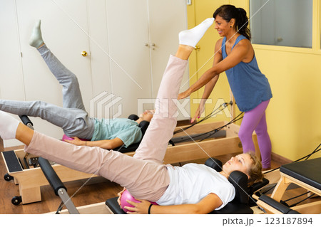 Female trainer working with girl and boy at gym. Female trainer helping teenager boy and girl 123187894