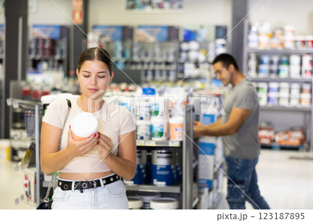 Positive girl planning to make house renovation, choosing paints in store 123187895