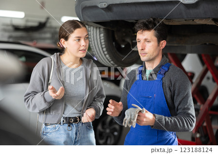 Male auto mechanic discussing with woman the cost and time to repair her car at car service Male auto mechanic discussing with woman the cost and time to repair her car at car service 123188124