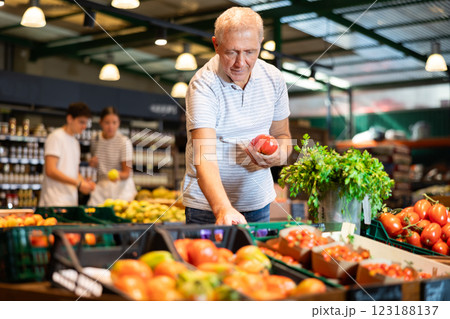 Elderly man chooses tomatoes in grocery store 123188137