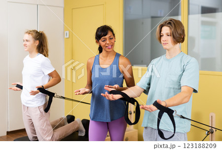 Teens doing pilates exercises with trainer 123188209