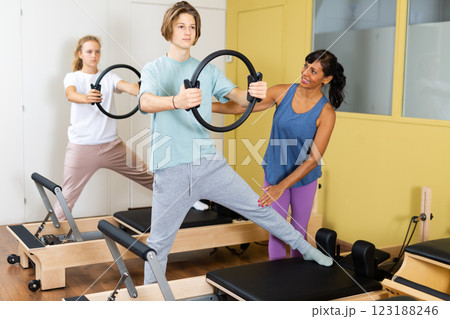 Teens doing pilates exercises with trainer 123188246