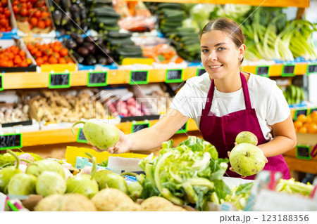 Portrait of happy woman in apron selling organic zucchini in shop 123188356