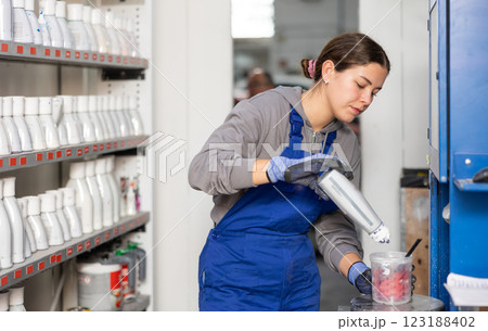Girl colorist selects paint color by mixing different paint colors for subsequent painting of car in car service center 123188402