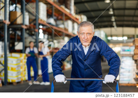 Elderly loader man pushing cart in warehouse Elderly loader man pushing cart in warehouse 123188457