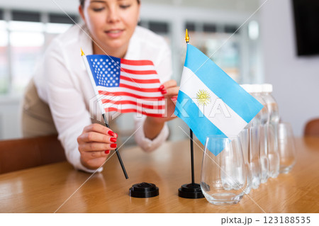Employee of delegation prepares negotiating table - sets up flag of United States and Argentine Employee of delegation prepares negotiating table - sets up flag of United States and Argentine 123188535