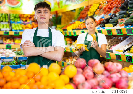 Handsome european male seller posing and offering different fruit in supermarket Handsome european male seller posing and offering different fruit in supermarket 123188592