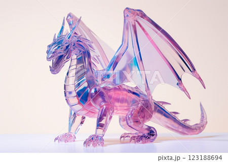 A dragon with a pink and blue body and wings. The dragon is sitting on a white table A dragon with a pink and blue body and wings. The dragon is sitting on a white table 123188694
