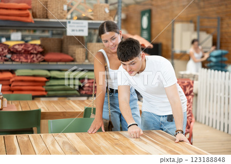 Young married couple chooses wooden table for their garden in garden store 123188848