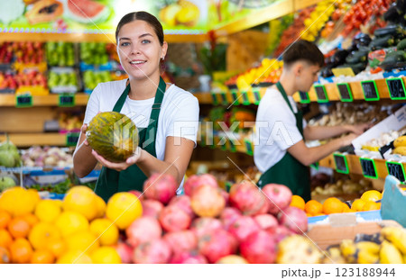 Young female seller puts melons on the counter Young female seller puts melons on the counter 123188944