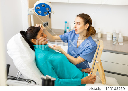 Beautician examining face skin of female patient 123188950