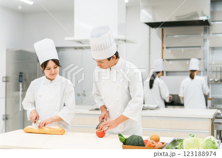 キッチンで仕込みをするコックコート姿の男女スタッフ（調理師・料理人・生鮮市場・食品加工） 123188974