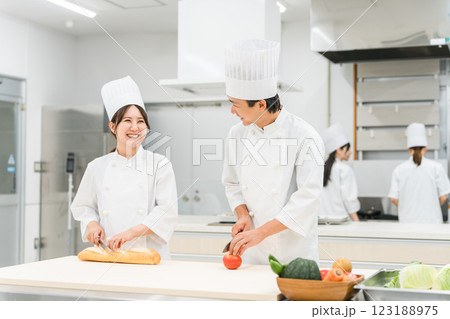 キッチンで仕込みをするコックコート姿の男女スタッフ(調理師・料理人・生鮮市場・食品加工) キッチンで仕込みをするコックコート姿の男女スタッフ(調理師・料理人・生鮮市場・食品加工) 123188975