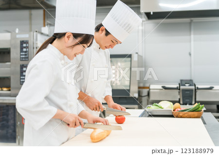 キッチンで仕込みをするコックコート姿の男女スタッフ（調理師・料理人・生鮮市場・食品加工） 123188979