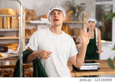 Dismissive young bakery worker ignoring coworker complaints Dismissive young bakery worker ignoring coworker complaints 123188990