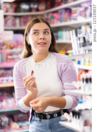 Stylish dreamy woman testing new lipstick, shopping in cosmetics store 123189037
