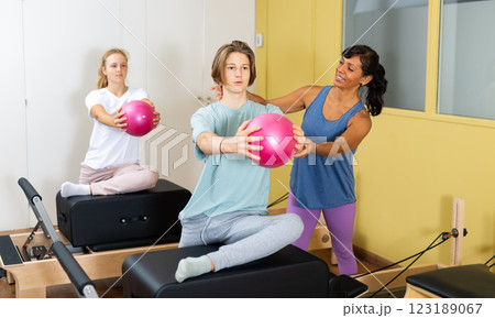 Pilates instructor shows boy how to exercise with ball 123189067