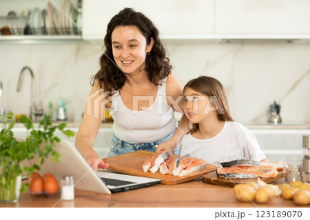 Happy mother and her daughter preparing salmon in the kitchen 123189070