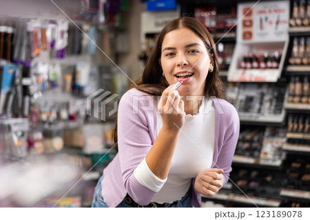 Woman testing new lipstick, shopping in cosmetics store Woman testing new lipstick, shopping in cosmetics store 123189078