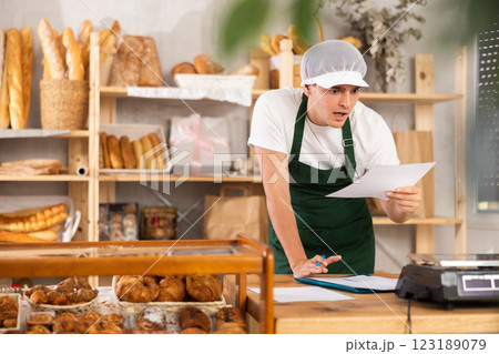 Surprised bakery worker reviewing unexpected order details 123189079