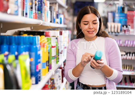 Styling young female choosing hair of body care spray and other products at shop 123189104