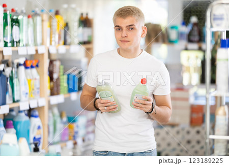 Focused young man choosing dishwashing liquid on supermarket shelf 123189225