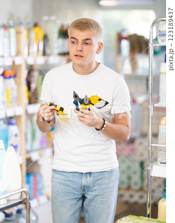 Guy selects various tools - screwdrivers, pliers for repairs in supermarket 123189437