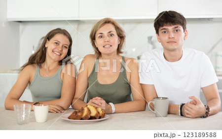 Positive woman is sitting at table between near young guy and girl 123189588