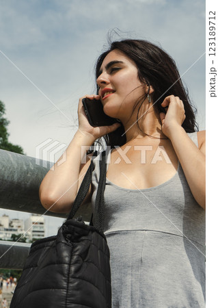 Young woman talking on smartphone and touching her hair outdoors Young woman talking on smartphone and touching her hair outdoors 123189712