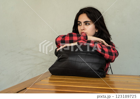 Sad young woman leaning on a pillow at a wooden table 123189725