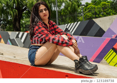Young woman posing sitting on red concrete block in urban park 123189738