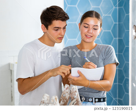 Young couple with documents checks the number of tiles, making important notes Young couple with documents checks the number of tiles, making important notes 123190015