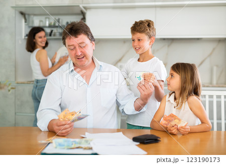 Head of family gives his wife and children pocket money 123190173