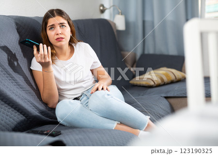 Disappointed woman talking on phone at home 123190325