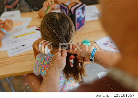 close up view of grandmother making braid to her small granddaughter close up view of grandmother making braid to her small granddaughter 123191657