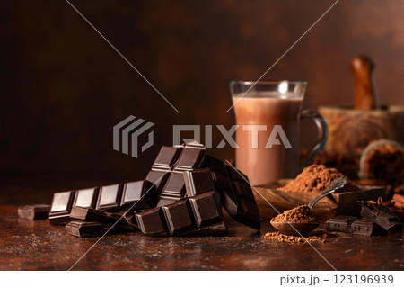 Pieces of bitter chocolate and glass of cocoa drink on a brown table. 123196939