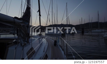 Sailboats anchored in tranquil sunset harbor with calm waters 123197557