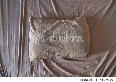 Wrinkled beige pillow on matching bed sheets creating a cozy restful ambiance 123197959