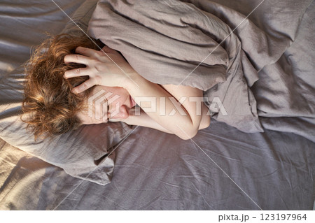 Caucasian female adult experiencing stress or anxiety while lying in bed under Caucasian female adult experiencing stress or anxiety while lying in bed under 123197964