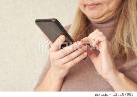 Mature caucasian woman using smartphone in cozy sweater indoors 123197983