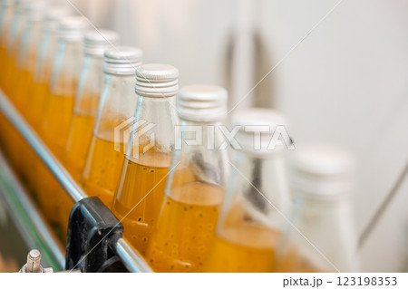 In a beverage factory an automated line fills transparent bottles with basil or chia seed drinks infused with pomegranate. The process is clean ensuring a high-quality liquid product. In a beverage factory an automated line fills transparent bottles with basil or chia seed drinks infused with pomegranate. The process is clean ensuring a high-quality liquid product. 123198353