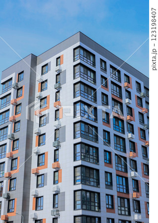 The concept of modern architecture, a residential complex, an apartment building for living. Close-up of a multi-storey, apartment building in gray and white tones with orange inserts of modern 123198407