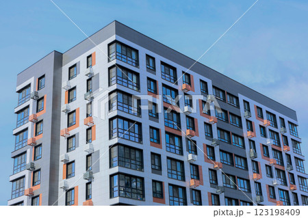 The concept of modern architecture, a residential complex, an apartment building for living. Close-up view from the corner of a multi-storey, apartment building in gray and white tones with orange The concept of modern architecture, a residential complex, an apartment building for living. Close-up view from the corner of a multi-storey, apartment building in gray and white tones with orange 123198409
