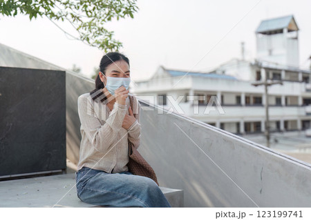 Young woman sitting outdoors, managing discomfort from pollution 123199741