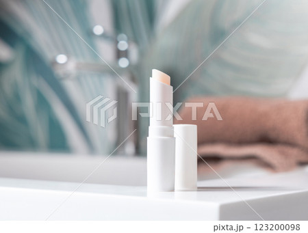 Opened white blank lip balm stick on basin in tropical bathroom close up, cosmetic mockup Opened white blank lip balm stick on basin in tropical bathroom close up, cosmetic mockup 123200098
