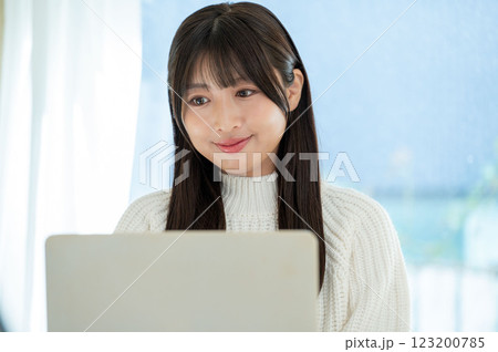 窓際でパソコン作業をする若い女性 窓際でパソコン作業をする若い女性 123200785