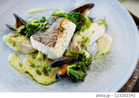 Cod fillet with cauliflower cream, asparagus, clam-wine sauce and mussles. Delicious seafood fish closeup served on a table for lunch in modern cuisine gourmet restaurant 123202342